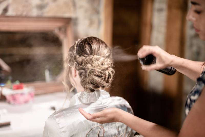 coiffeuse réalisant une coiffure chignon bas avec tresse en relief de mariée lors d'un mariage en Rhône alpes