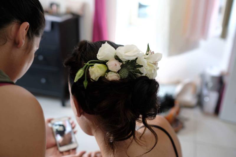 une mariée avec un chignon a semi hauteur flou et lâche avec un ornement fleur   et sa coiffeuse 